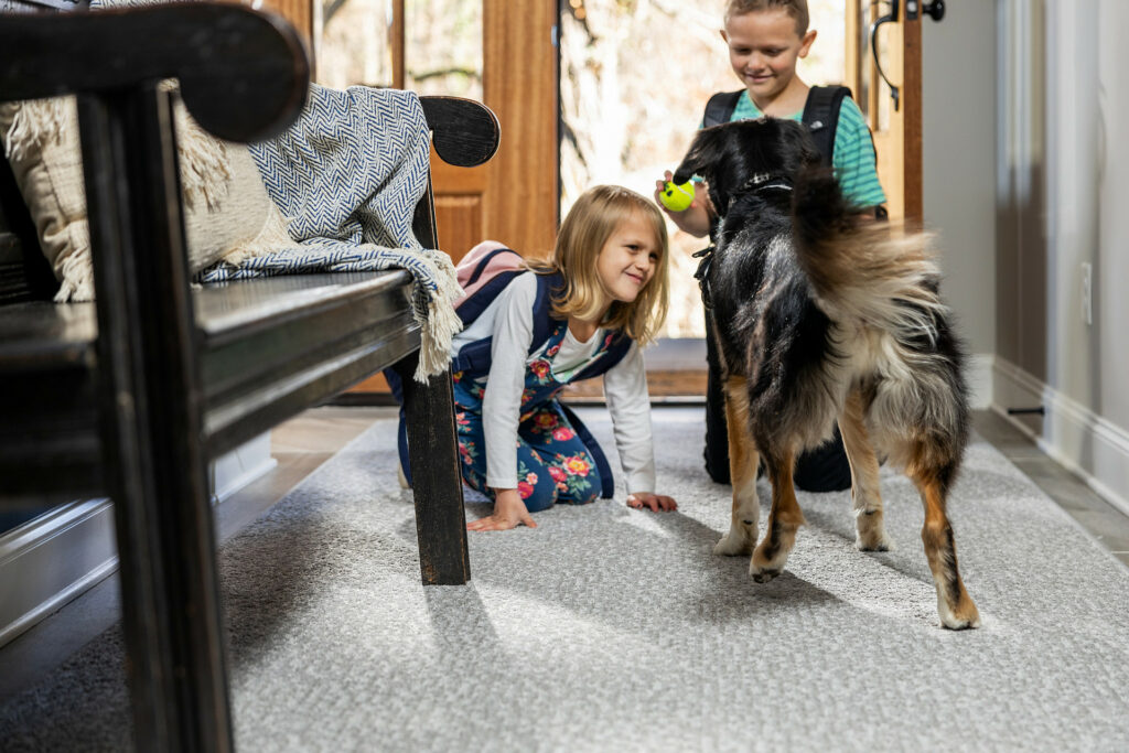 Kids plying with dog on carpet flooring | Flooring By Design NC